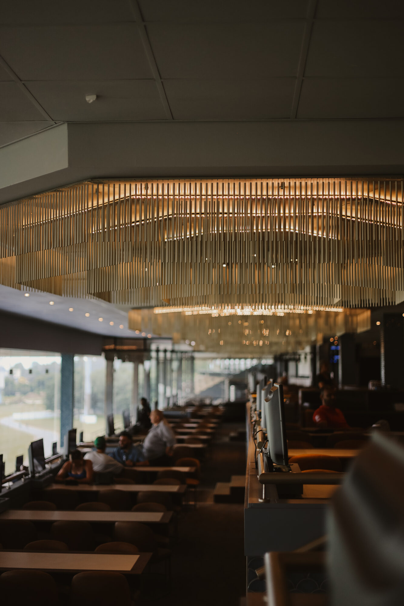 Linear rod chandelier lighting installation above a hospitality lounge seating area